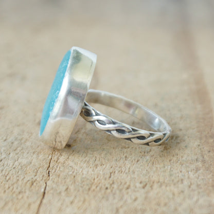 Teal sea glass ring with silver band on a wooden surface