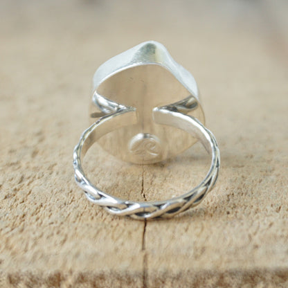 Teal sea glass ring with silver band on a wooden surface