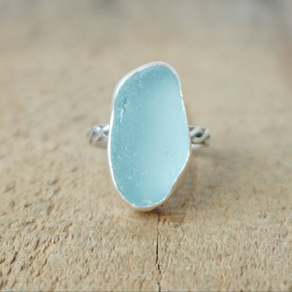 Ring with a light blue sea glass and silver band on a wooden surface