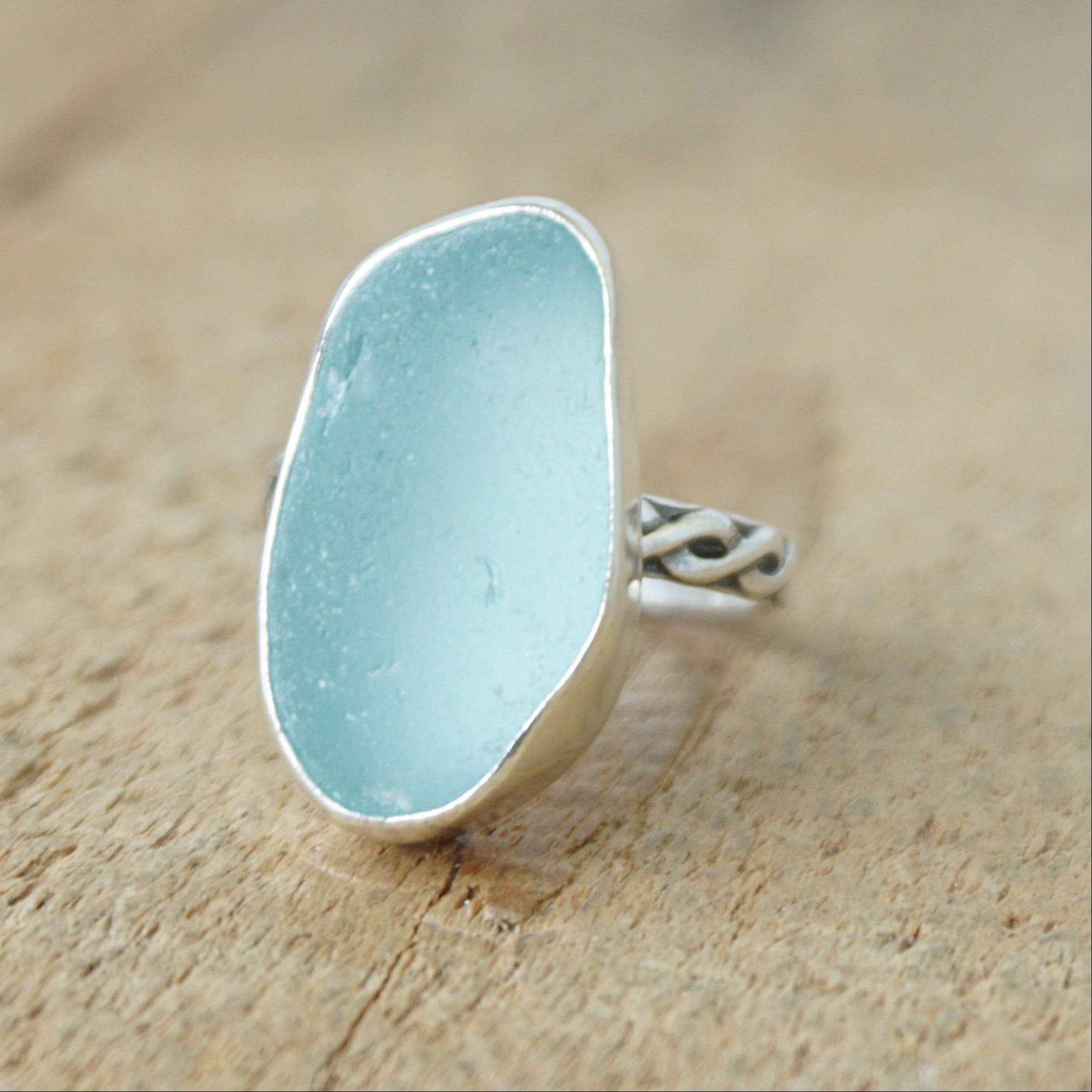 Ring with a light blue sea glass and silver band on a wooden surface