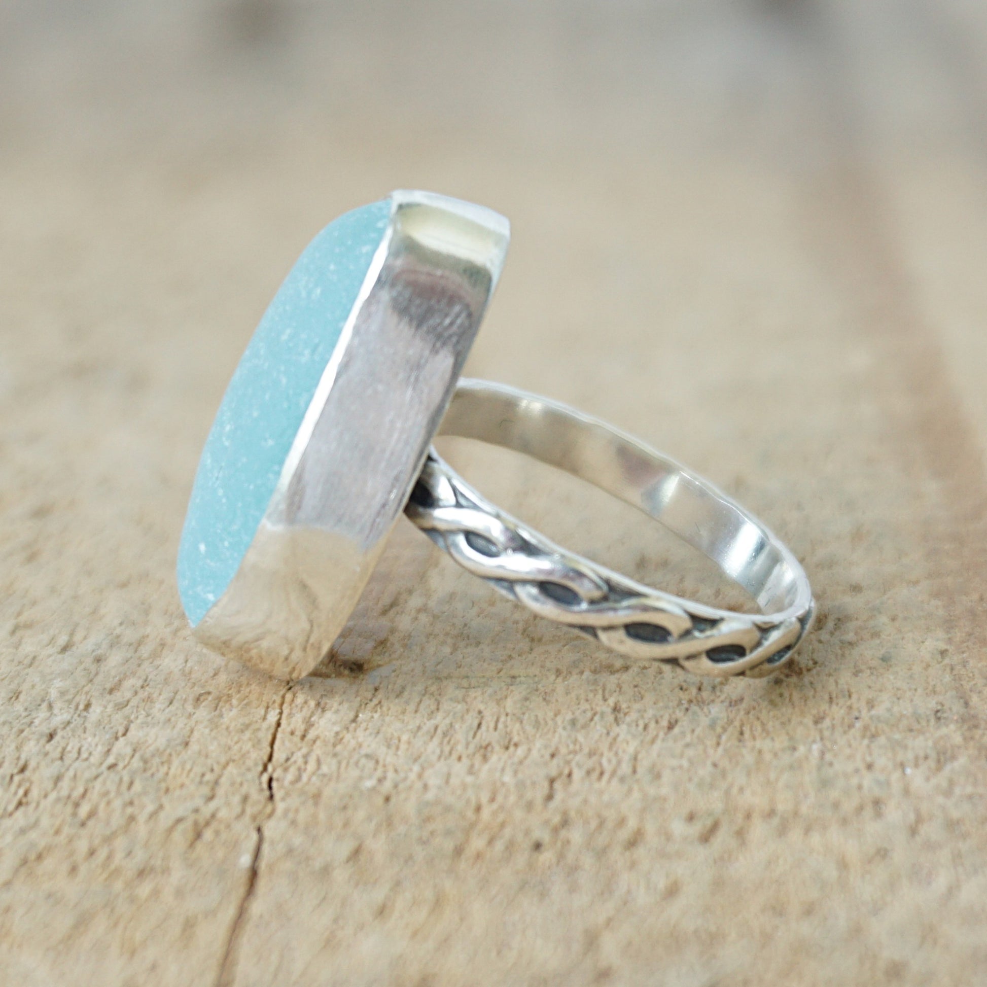 Ring with a light blue sea glass and silver band on a wooden surface