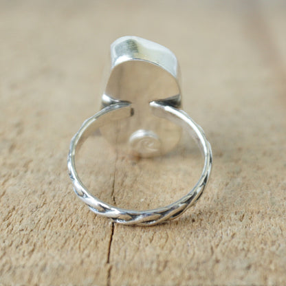 Ring with a light blue sea glass and silver band on a wooden surface