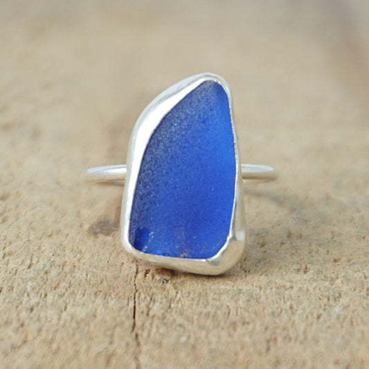 Blue sea glass ring with silver setting on a wooden surface
