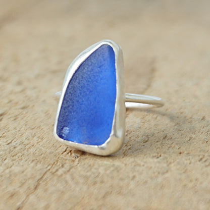 Blue sea glass ring with silver setting on a wooden background