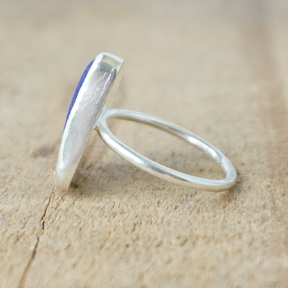 side view of a silver ring with blue sea glass on a wooden background