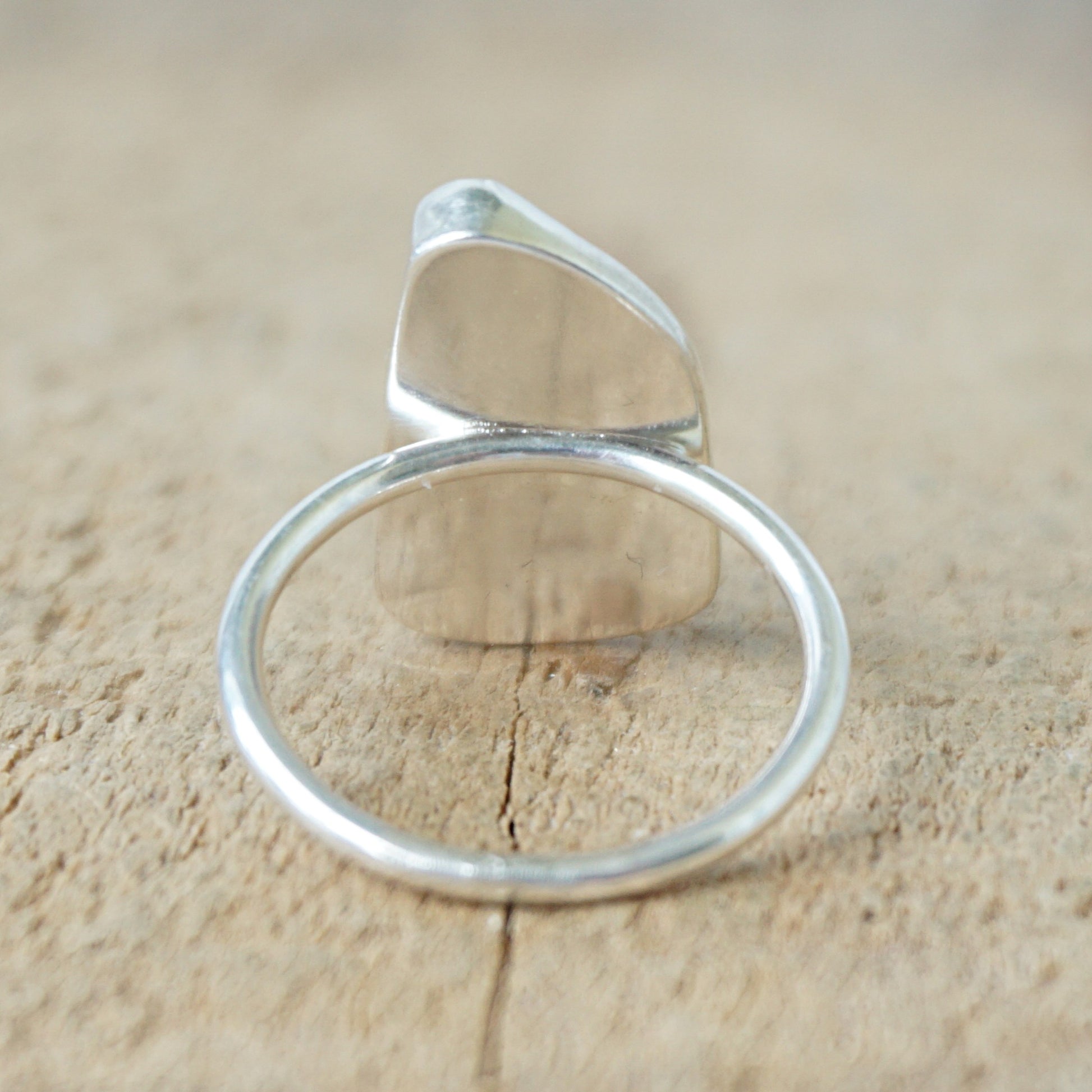 back view of a silver ring with blue sea glass on a wooden background
