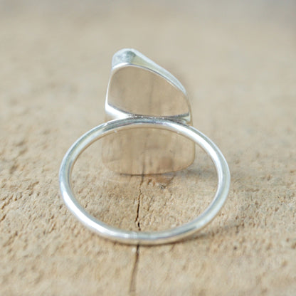 back view of a silver ring with blue sea glass on a wooden background