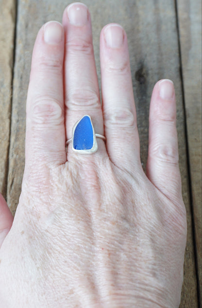 Hand wearing a blue ring on a wooden surface