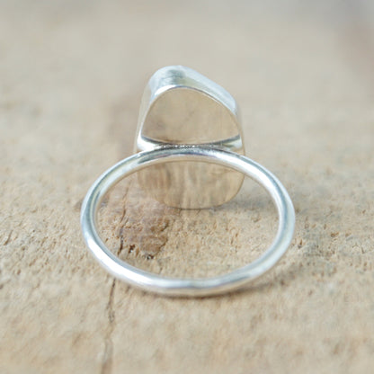back view of a silver ring with teal sea glass on a wooden background