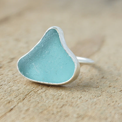 silver ring with teal sea glass on a wooden background