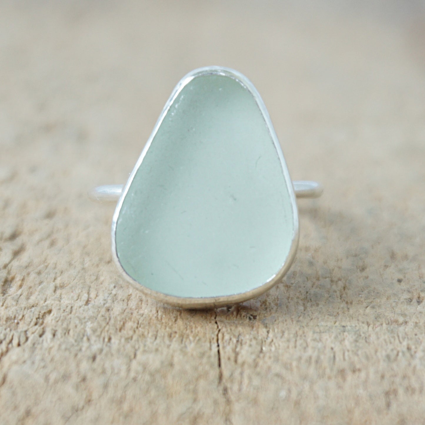 silver ring with seafoam green sea glass on a wooden background