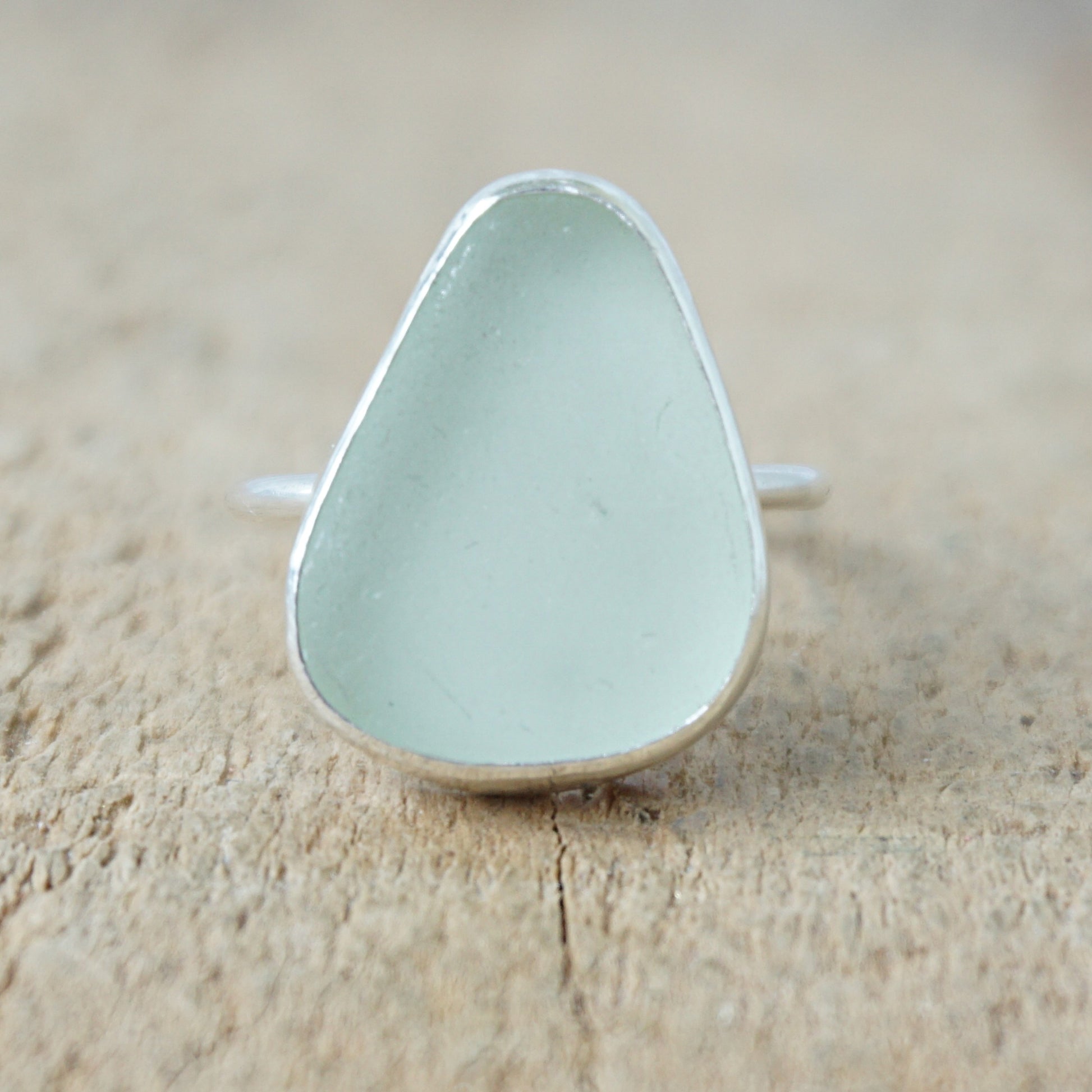silver ring with seafoam green sea glass on a wooden background