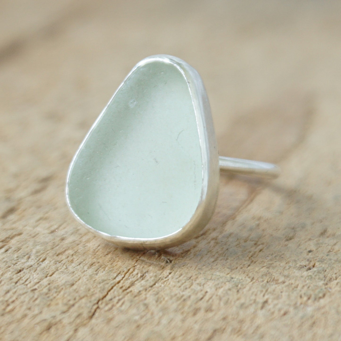 silver ring with seafoam green sea glass on a wooden background