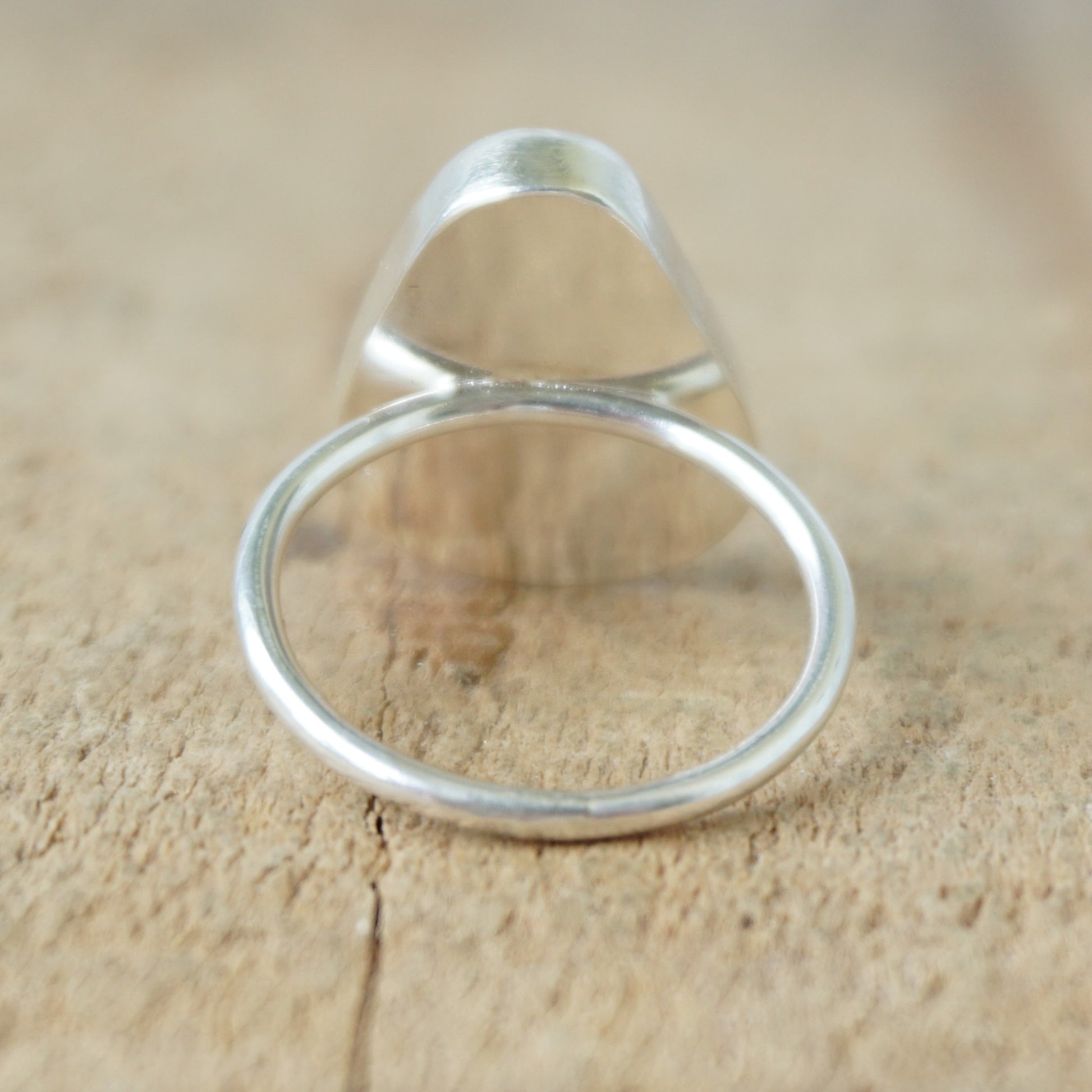 back view of a silver ring with seafoam green sea glass on a wooden background
