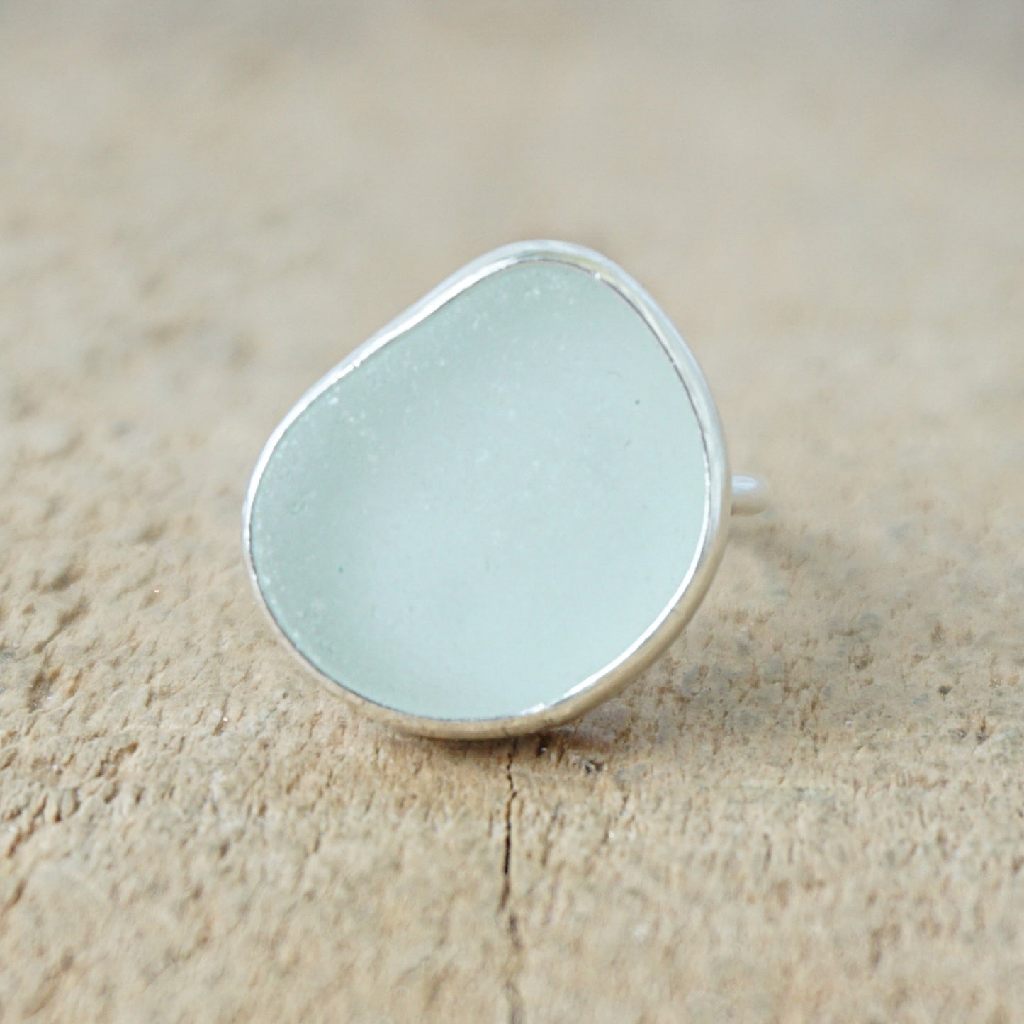 silver ring with seafoam green sea glass on a wooden background
