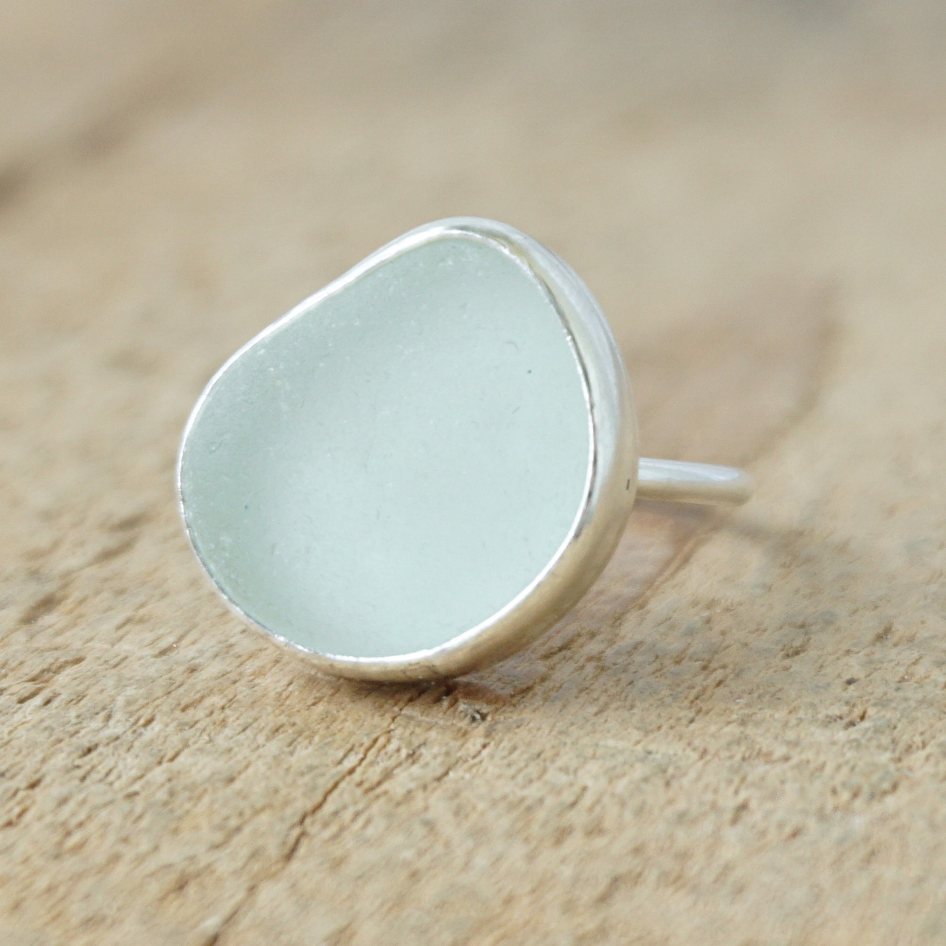 silver ring with seafoam green sea glass on a wooden background