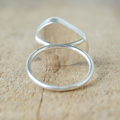 back view of a silver ring with seafoam green sea glass on a wooden background