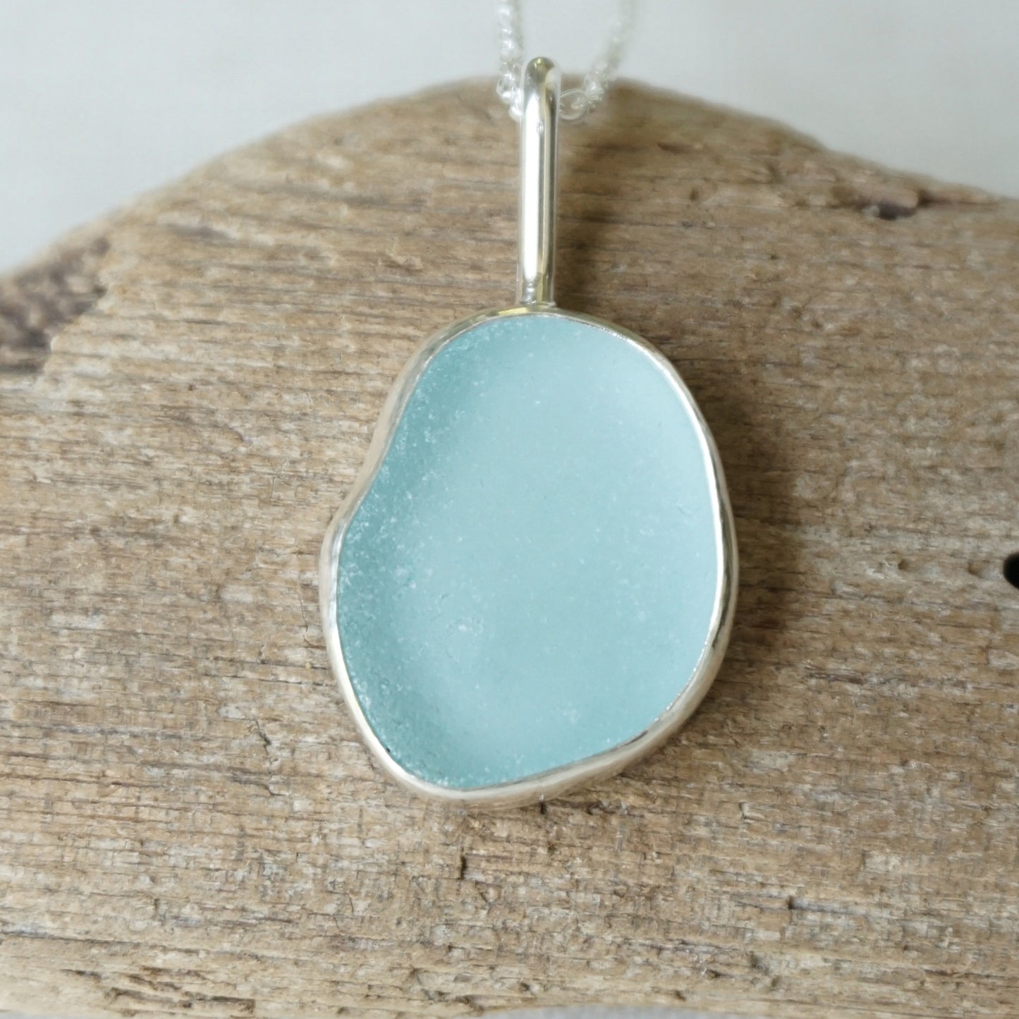 light blue sea glass pendant on a wooden background