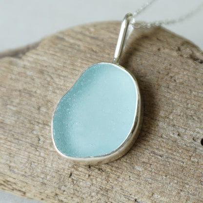 light blue sea glass pendant on a wooden background