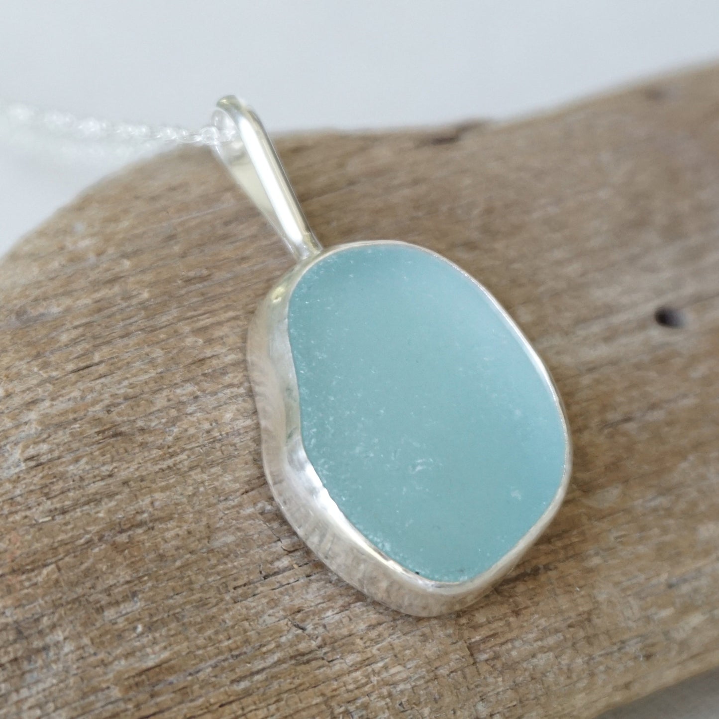 light blue sea glass pendant on a wooden background
