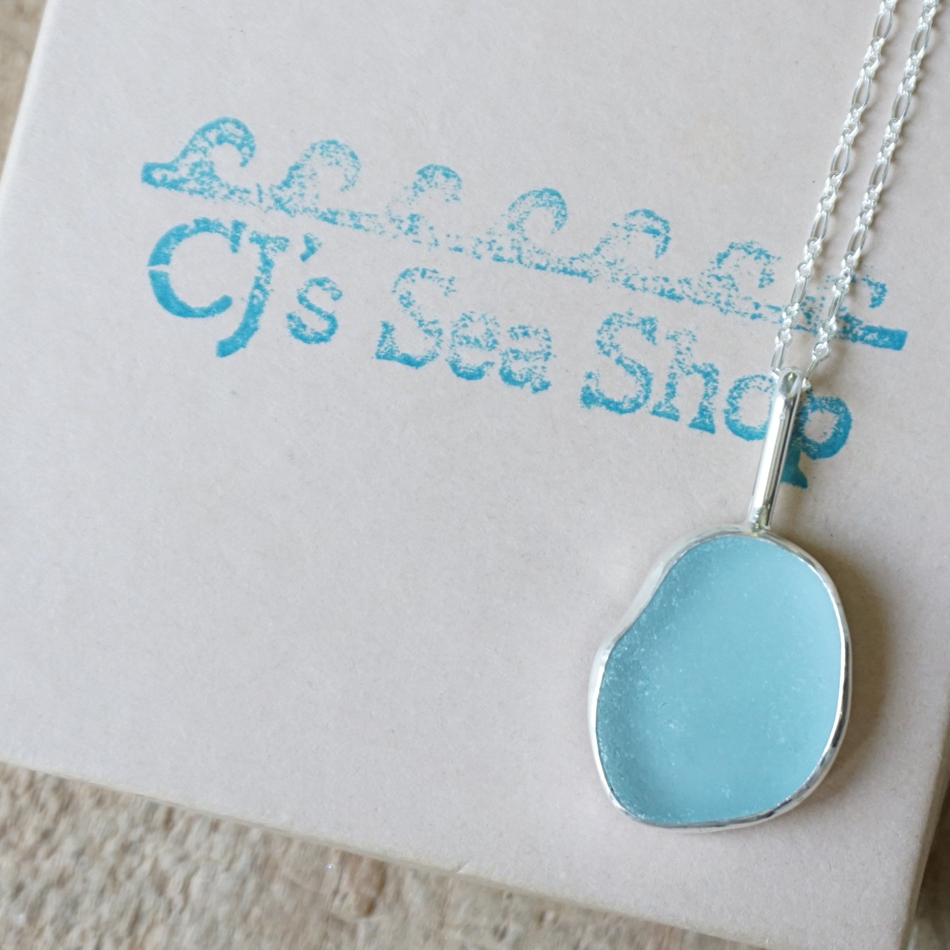 light blue sea glass pendant on a gift box