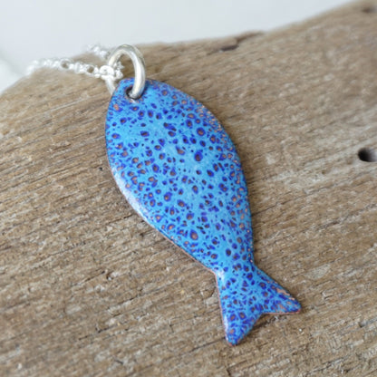 Blue speckled fish-shaped pendant on a wooden surface