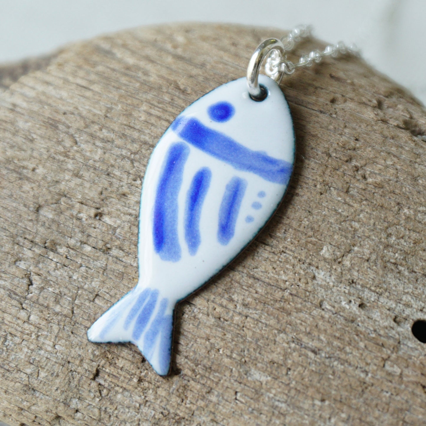 Fish-shaped pendant with blue design on a wooden surface