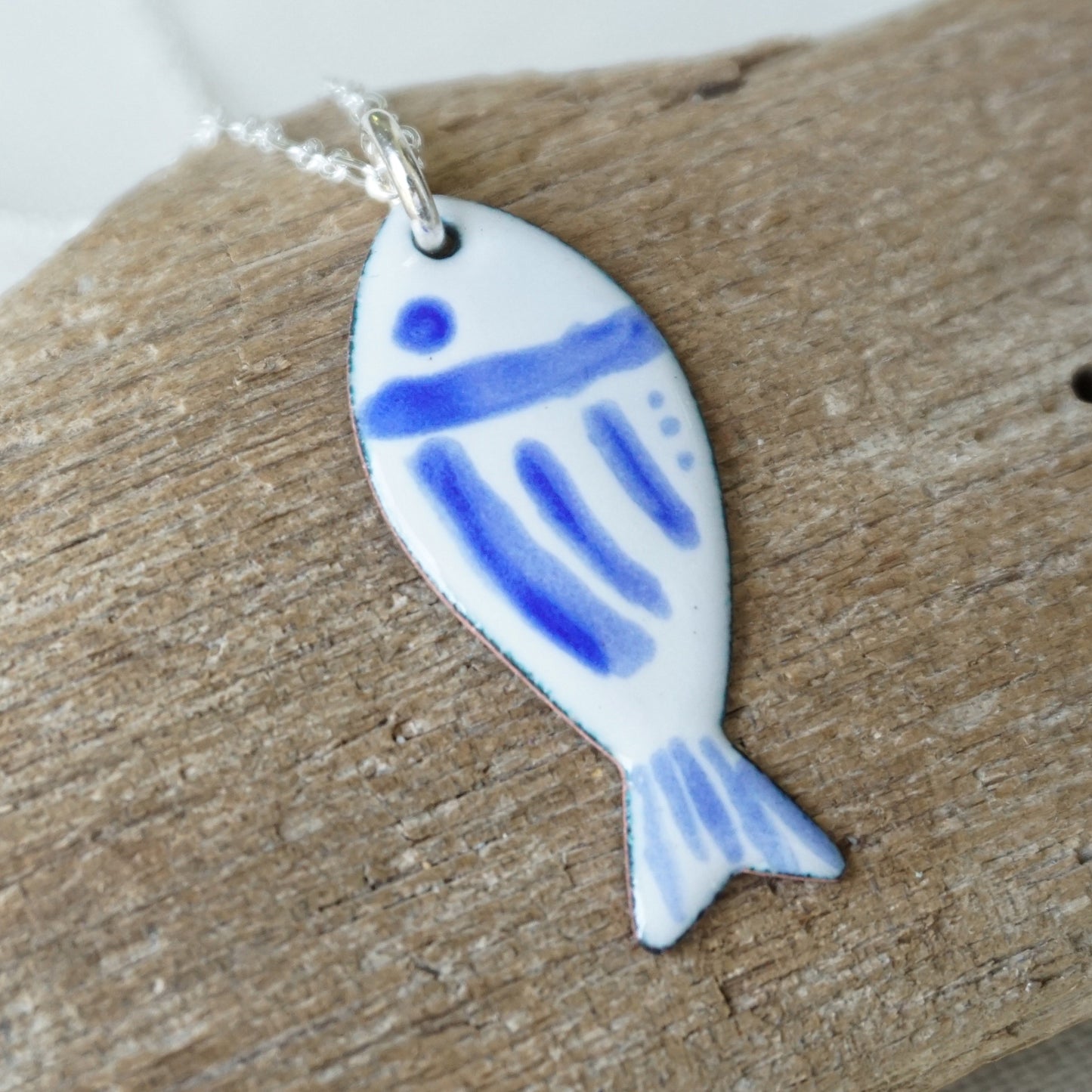 Fish-shaped pendant with blue design on a white background