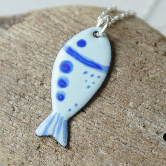Fish-shaped pendant with blue accents on a wooden surface
