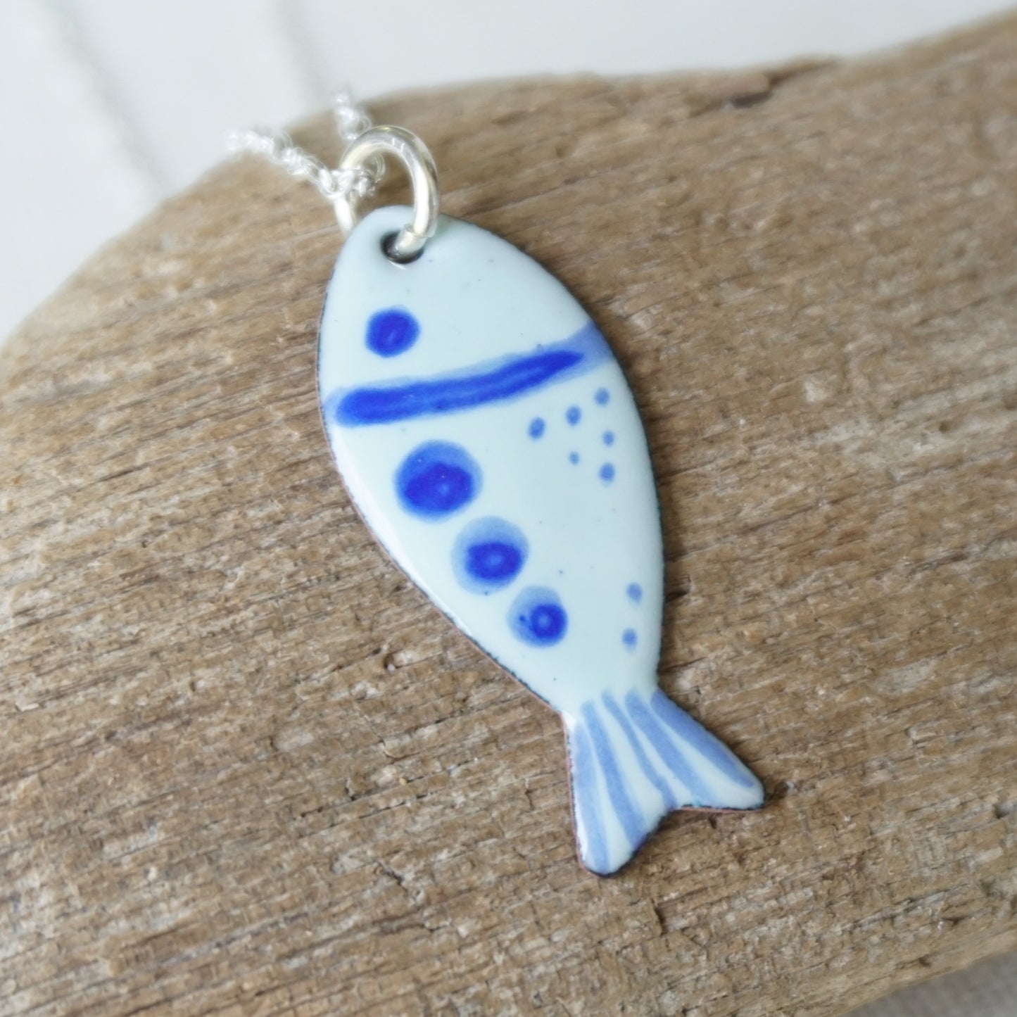 Fish-shaped pendant with blue accents on a wooden surface