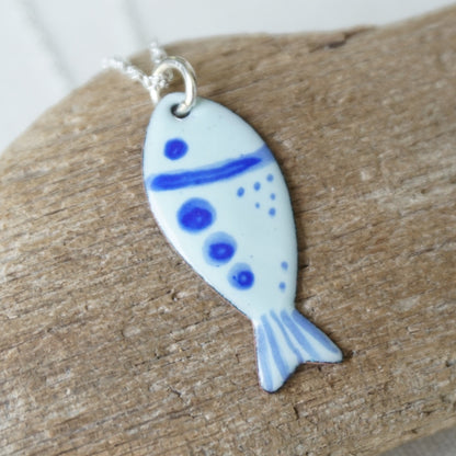 Fish-shaped pendant with blue accents on a wooden surface