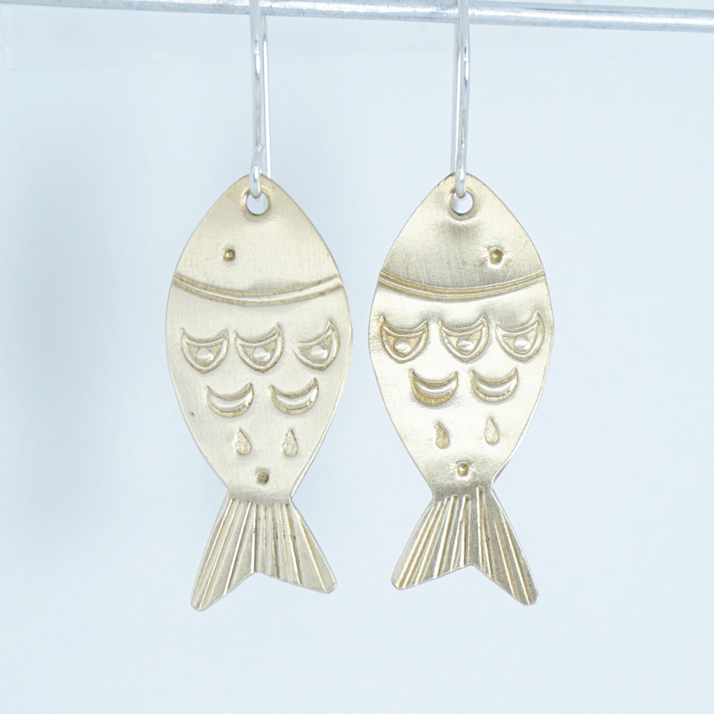 Gold fish-shaped earrings on a white background
