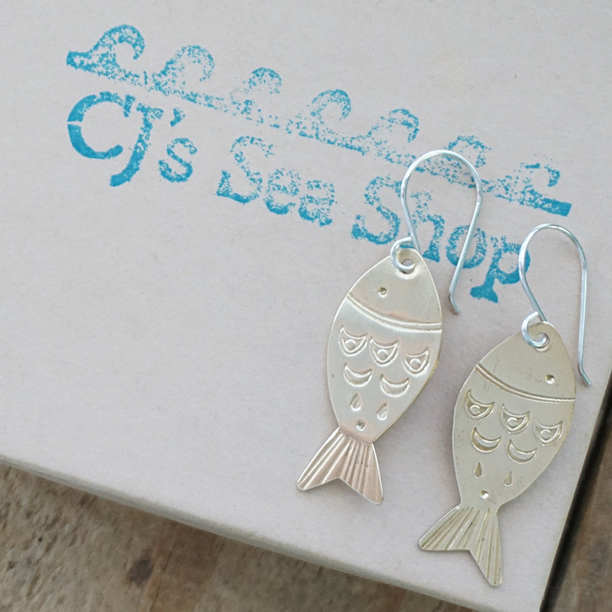Brass fish-shaped earrings on a gift box