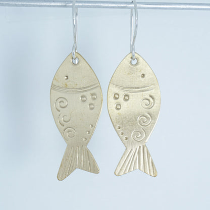 Brass fish-shaped earrings on a white background