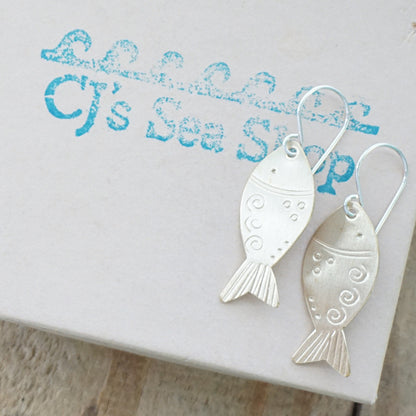 Brass fish-shaped earrings on a gift box