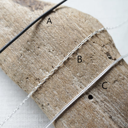 Three chain options available. Leather, Sterling link, or sterling foxtail. Chains shown on a wooden background.